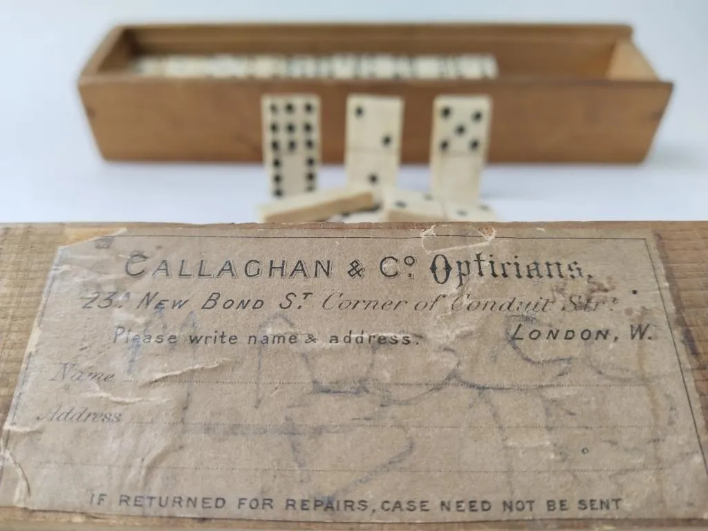 Antique domino set from Callaghan & Co. Opticians, crafted between 1870 and 1875, featuring bone pieces and a wooden case with a label from 23a New Bond Street, London.