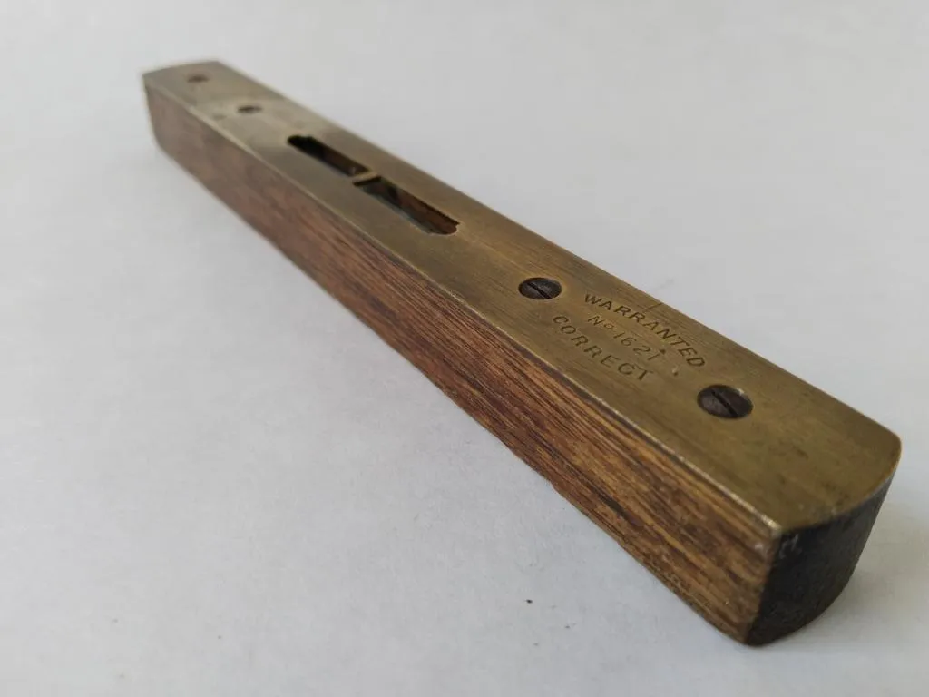 A close-up of the Hockley Abbey spirit level, model No. 1621, crafted from walnut wood and brass. This well-preserved tool, produced by John Rabone & Sons in the late 19th century, showcases the precision and craftsmanship of historical measuring instruments.