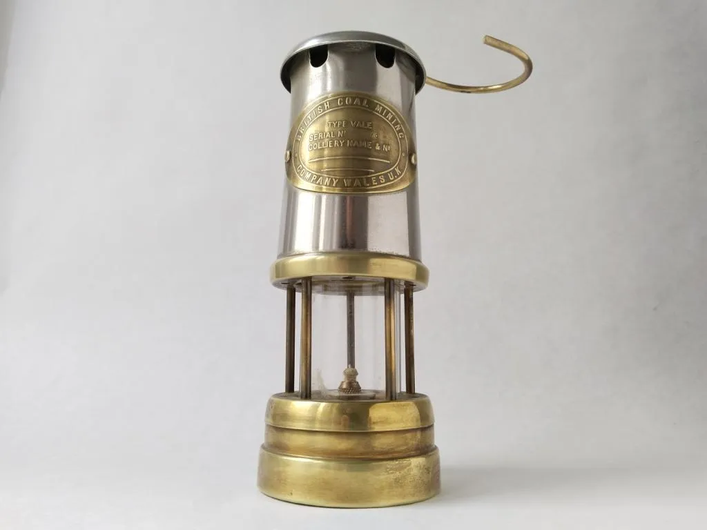 A vintage paraffin miner's lamp from the British Coal Miners Company, Wales, exemplifying the essential safety equipment used in early 20th-century coal mines.