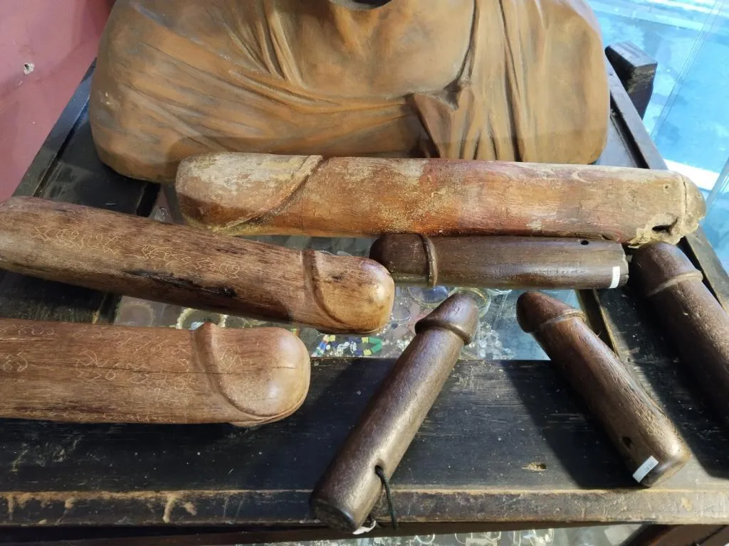 Phallic wooden amulets on display, often associated with ancient fertility and protection rituals.